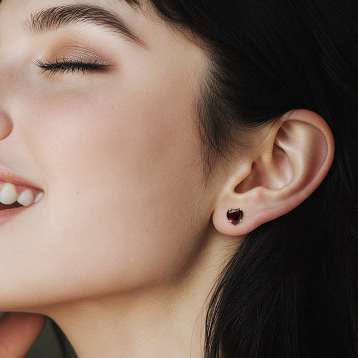 Garnet heart stud earrings in 14kt yellow gold on model’s ear