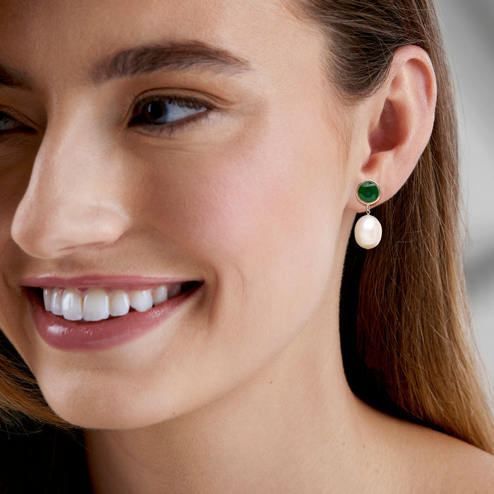 Yellow gold drop earrings on ear: emerald-green round top with white pearl drop